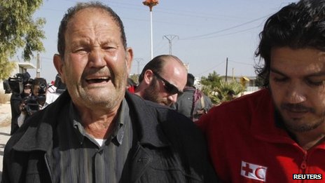 A volunteer from the Syrian Arab Red Crescent helps a weeping man 